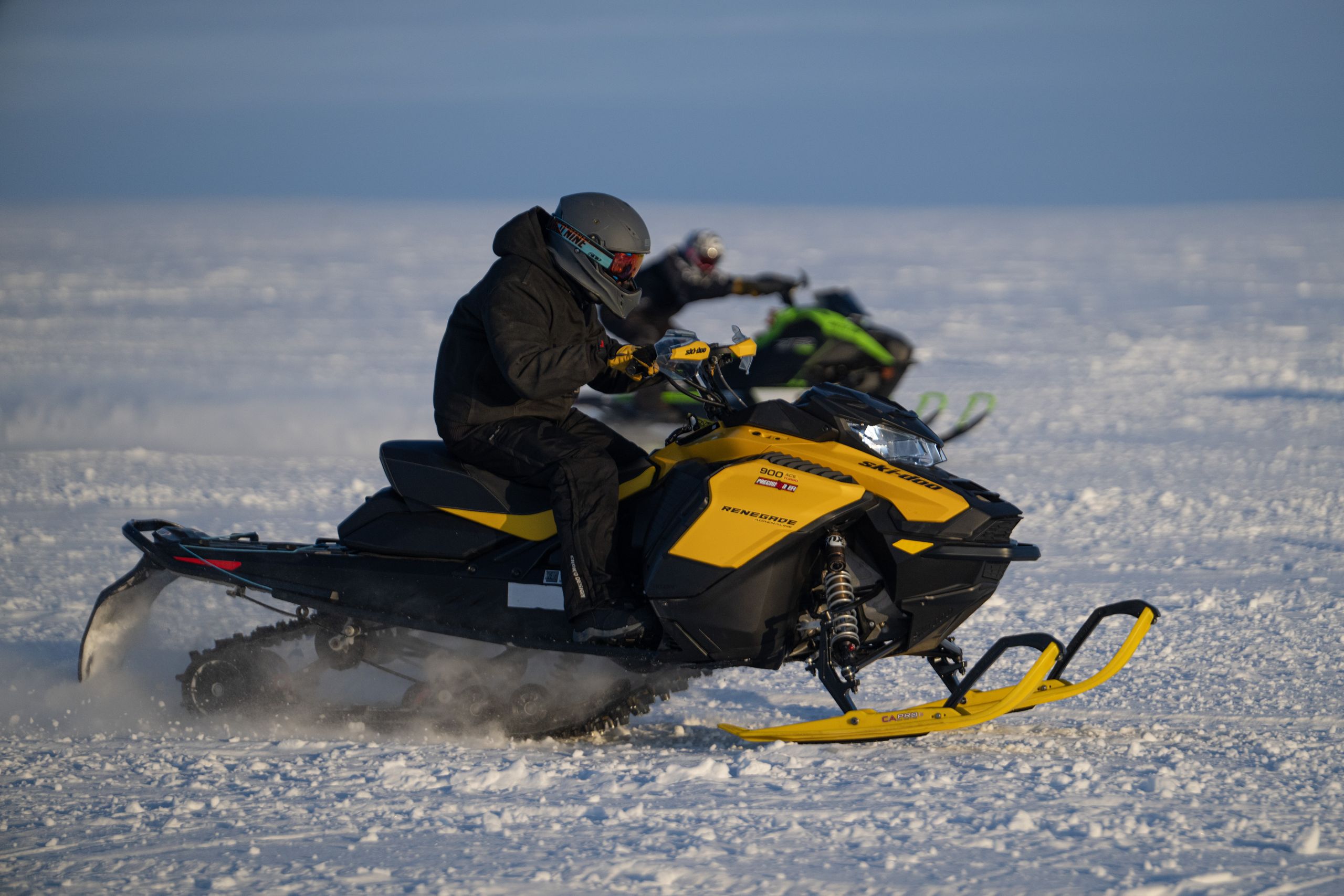 Snowmobiles race across an expanse of sea ice