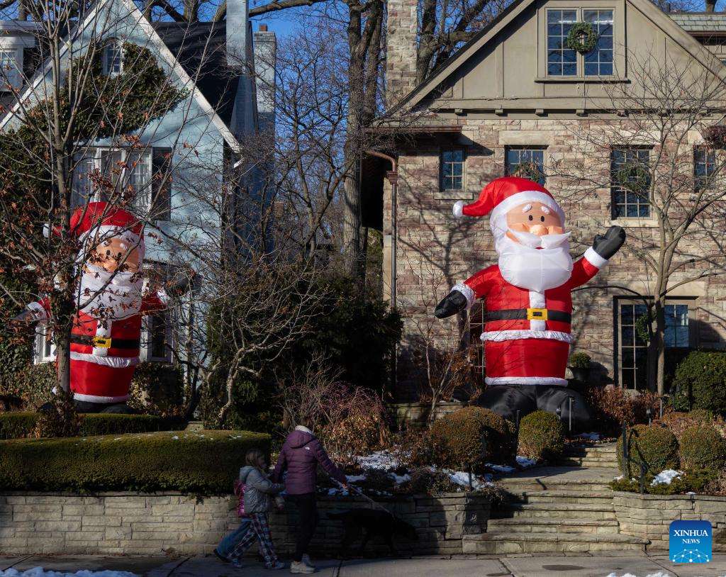 Giant-sized inflatable Santa Clauses seen on street in Toronto, Canada-Xinhua