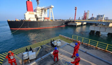 Staff members tie a mooring rope for a vessel carrying petrochemical raw materials at Yangpu Port in Danzhou, south China
