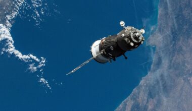 A gray spacecraft is seen floating above the ocean on Earth