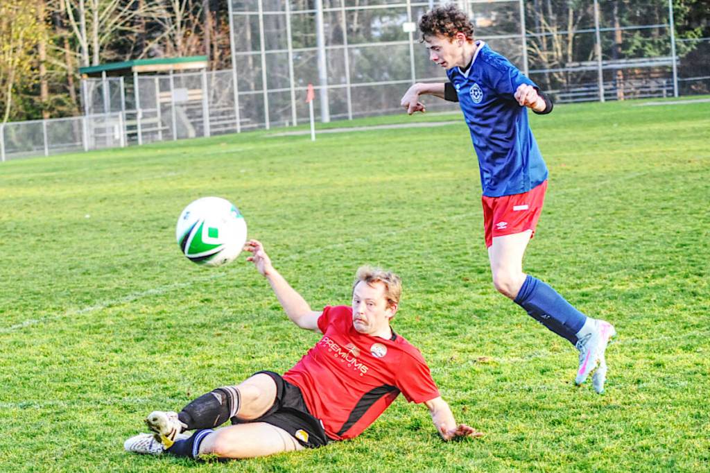 Parksvillians defender Jayson Matthews slides to kick the ball away from a charging Peninsula FC player. (Michael Briones photo)
