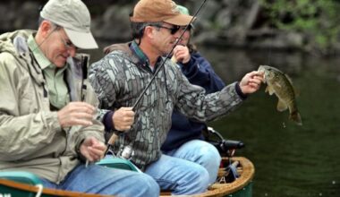 Russell Salisbury admires a smallmouth bass while fishing with Russell Duncan, left, both of Cary, N.C., and Maine guide Sue Hurd, on Big Lake near Grand Lake Stream, Maine, on May 31, 2006. (AP Photo/Robert F. Bukaty)