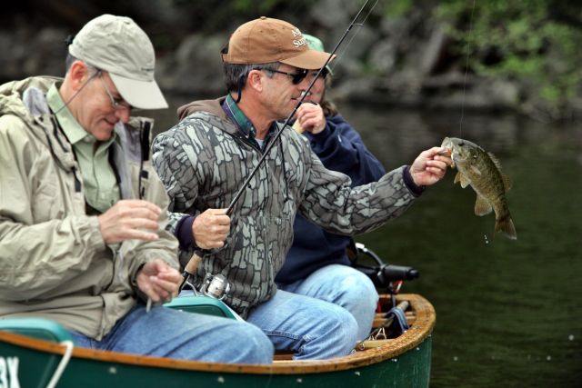 Russell Salisbury admires a smallmouth bass while fishing with Russell Duncan, left, both of Cary, N.C., and Maine guide Sue Hurd, on Big Lake near Grand Lake Stream, Maine, on May 31, 2006. (AP Photo/Robert F. Bukaty)