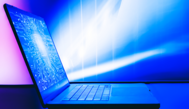 A laptop with a bright image of a digital printed circuit board on the screen.