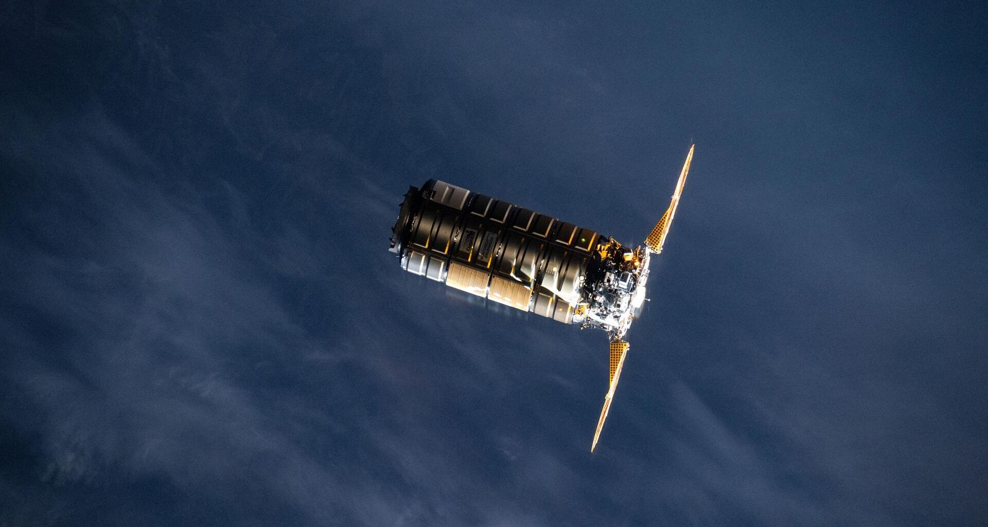 A metal spacecraft with two solar panels on either side is seen in low-Earth orbit