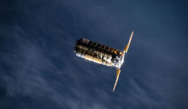 A metal spacecraft with two solar panels on either side is seen in low-Earth orbit