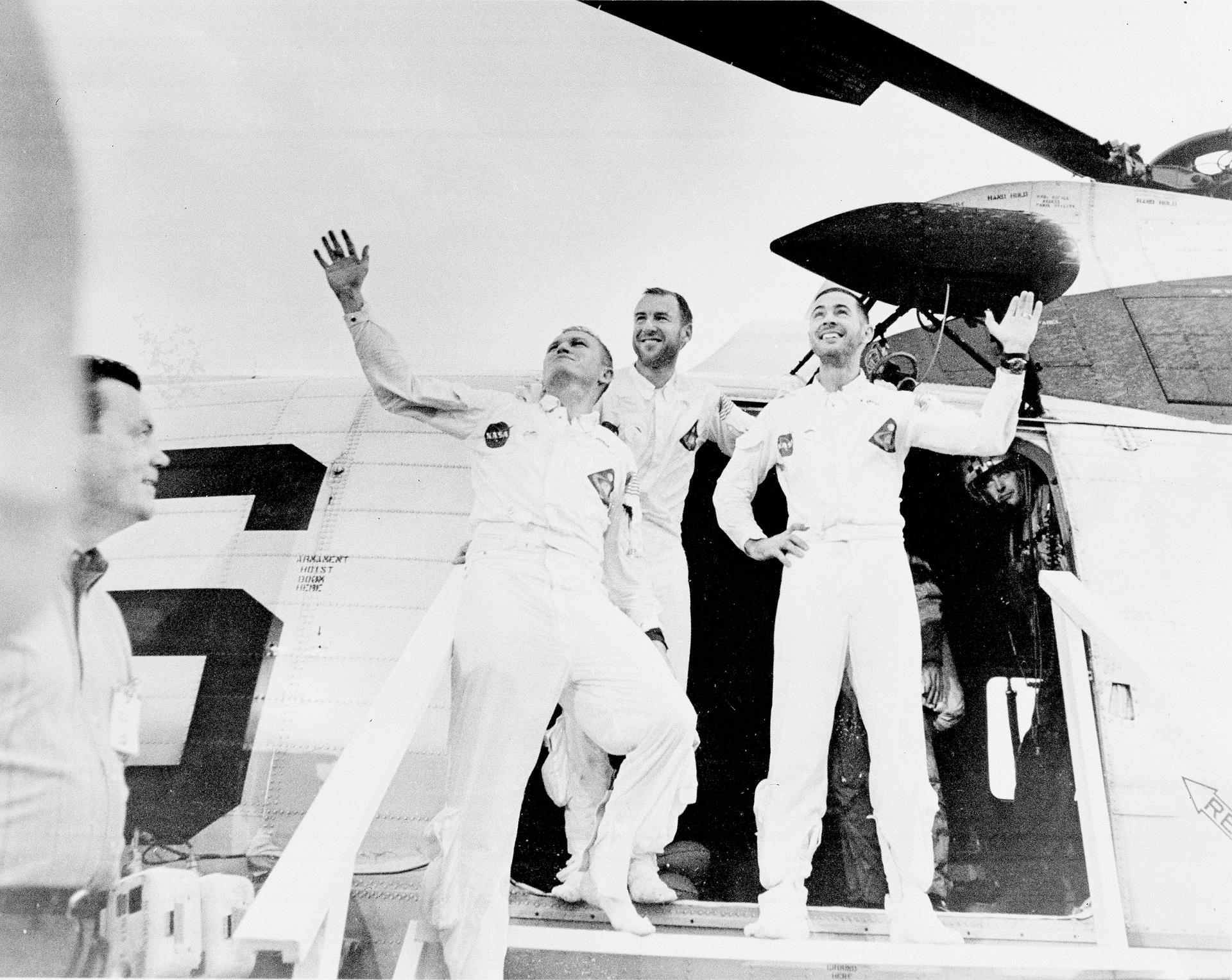 A black and white image of the astronauts of Apollo 8 waving after leaving their recovery helicopter on Dec. 27, 1968. From left, they are: William Anders, Jim Lovell and Frank Borman.