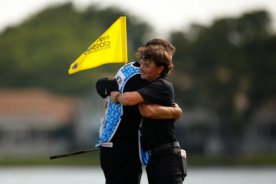 Amateur Luke Clanton of the United States hugs his caddie Jason Wiertel on the 18th hole during the final round of the Cognizant Classic in The Palm Beaches 2025 at PGA National Resort And Spa on March 02, 2025 in Palm Beach Gardens, Florida.
