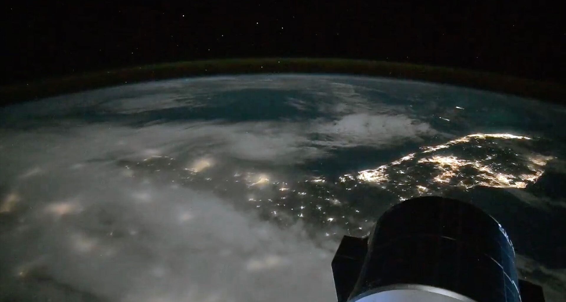 a lights from cities along the coast of a peninsula are seen at night from space