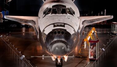 a winged back and white orbiter standing on its landing gear is seen on museum display