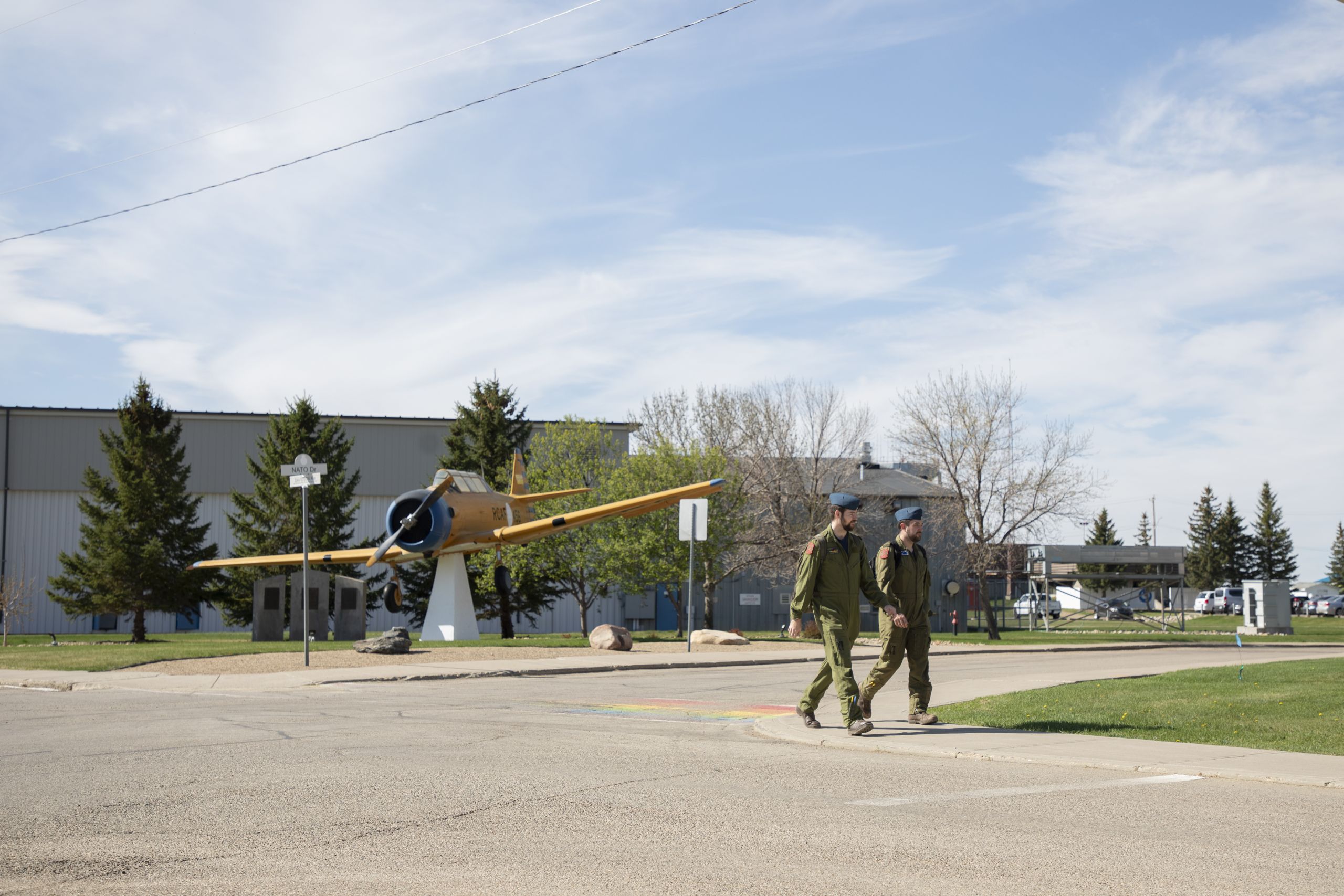 Two military personnel in uniform walk past a plane on display