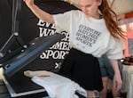 Thea Owens uses a heat press machine to add the Portland Fire logo to a t-shirt at the launch party for the Fire, Portland’s new WNBA team, at the Moda Center in Portland, Ore., July 15, 2025. 