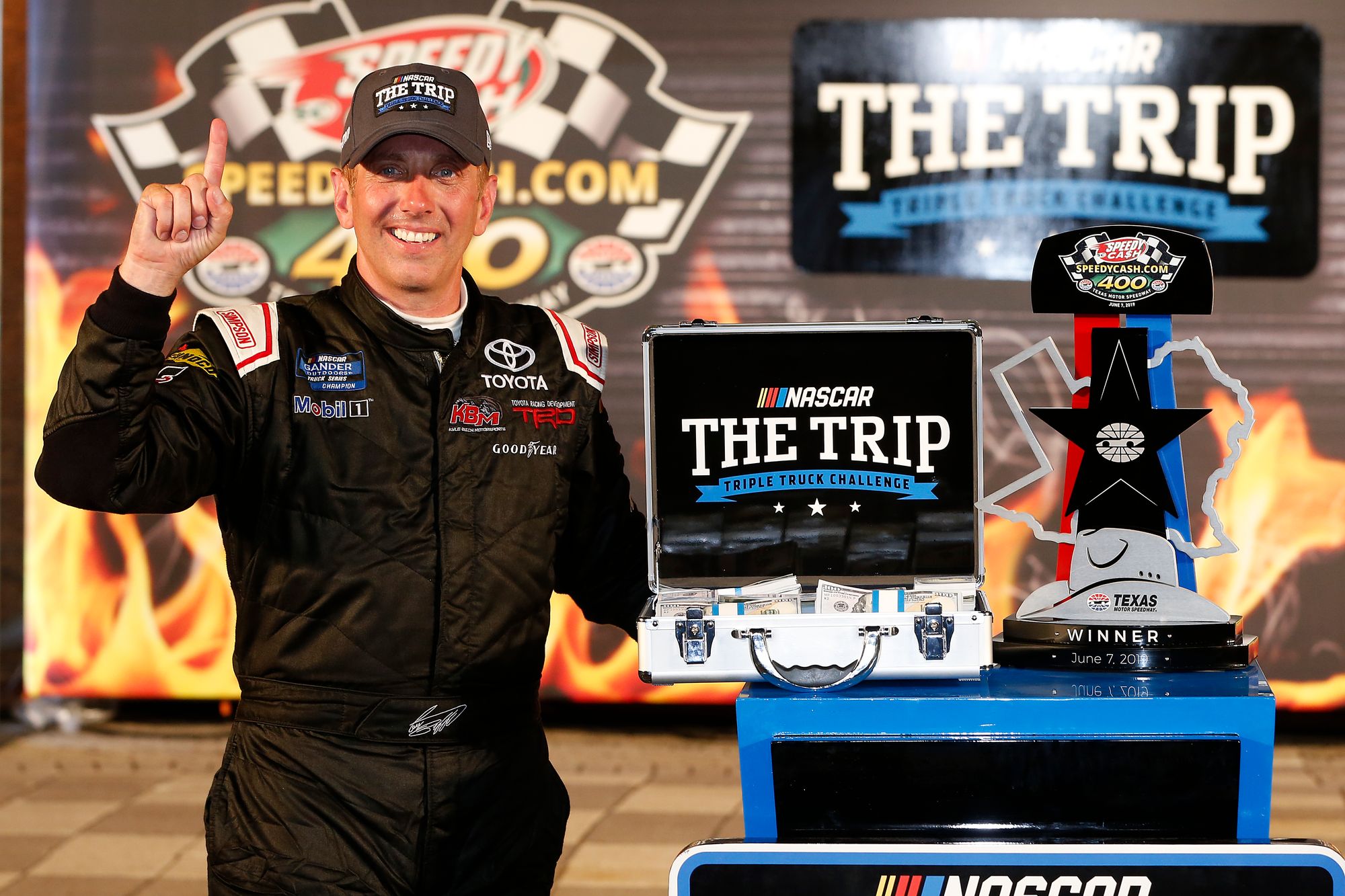 Greg Biffle poses with a trophy and cash prize in 2019