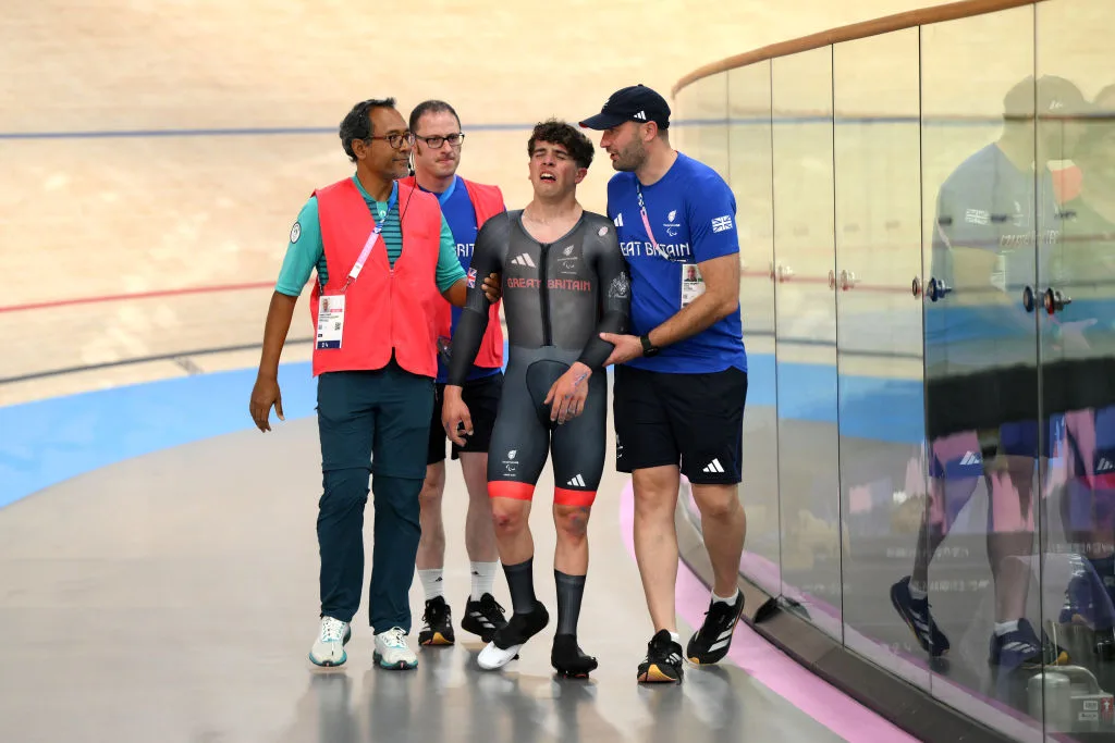 Archie Atkinson is assisted by Team GB staff after crashing in the final of the men's C4 individual pursuit at the Paris 2024 Paralympic Games