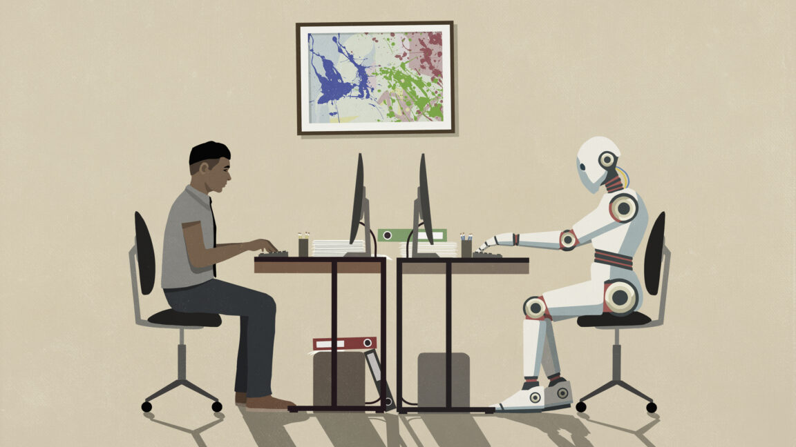 Man and humanoid robot working face to face at computers