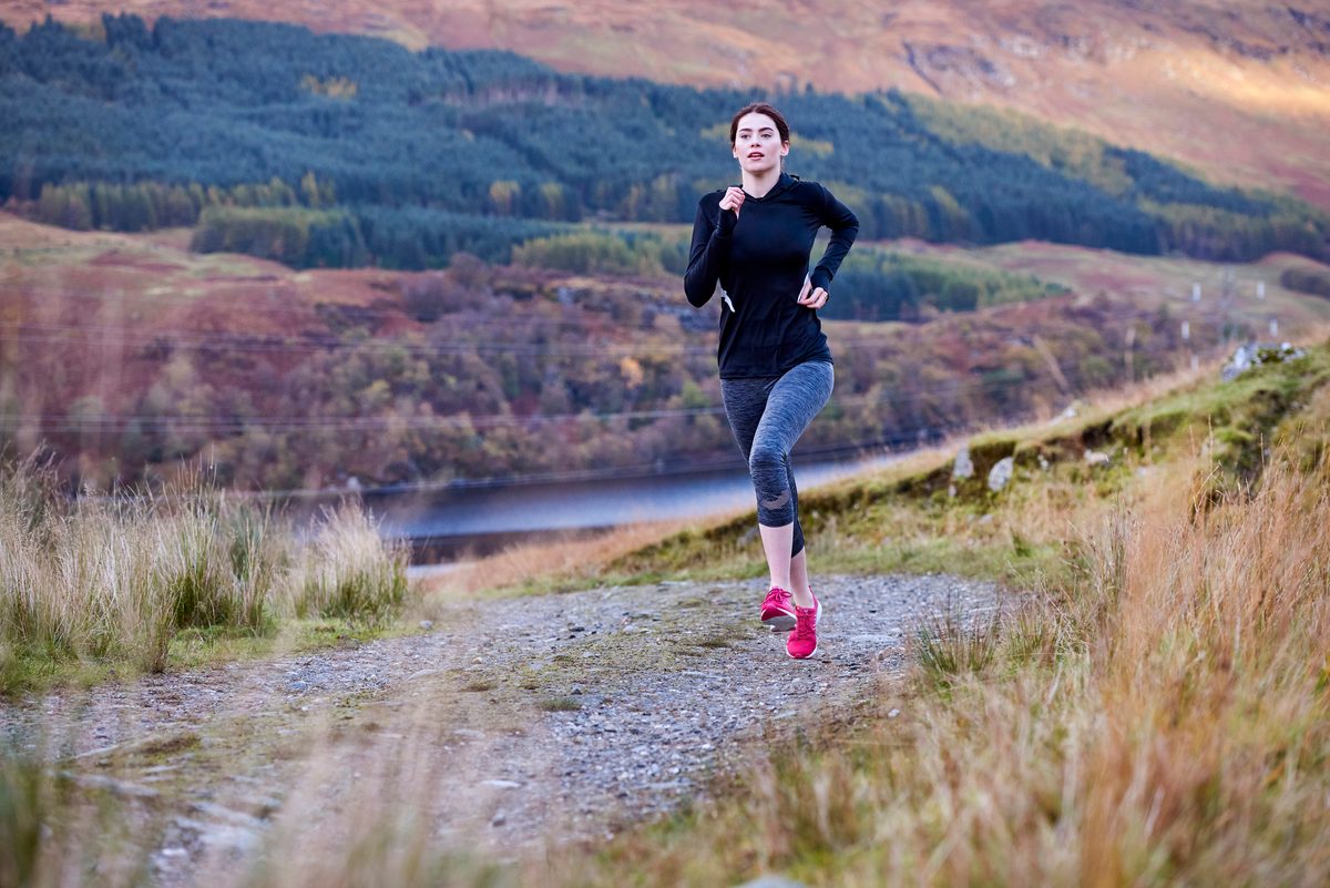 Woman running up a hill in the wilderness