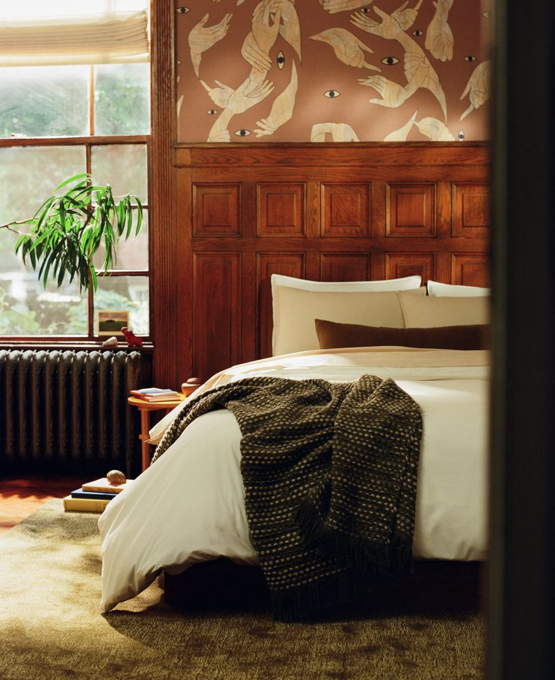 Brooklinen bedding styled in a bedroom with wooden wall panels and eccentric patterned wallpaper