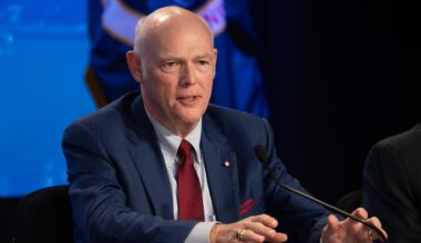 A man in a blue and white suit speaking into a microphone in a NASA press conference.