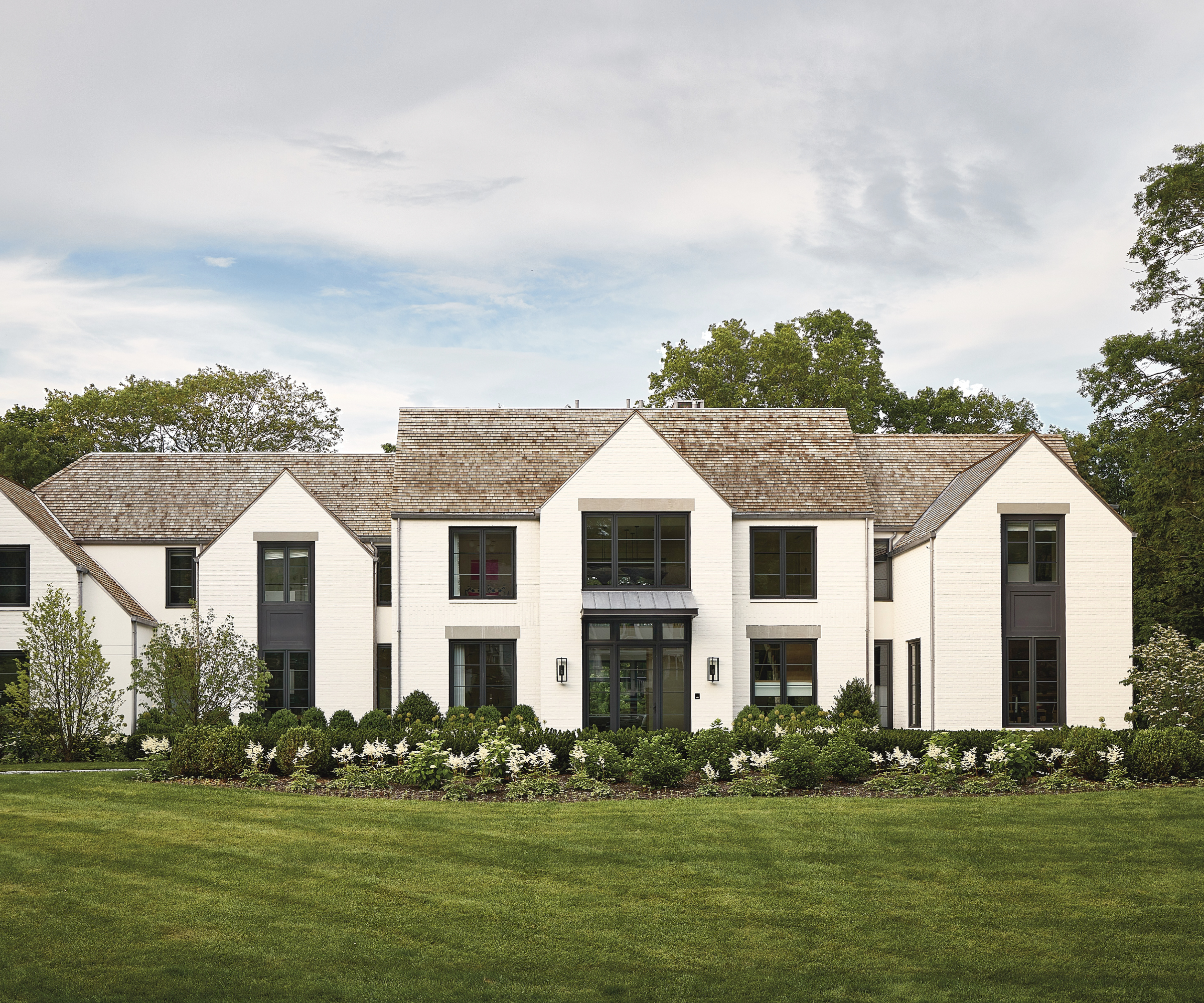 An exterior of a house with gabled roofs and a white surface.