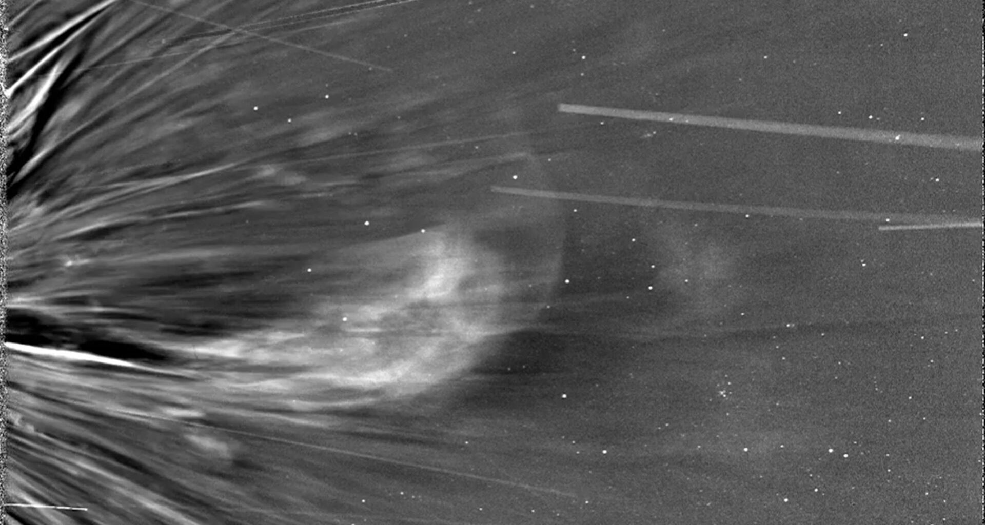 A grayscale image shows a close up of the sun and shows a solar wind changing direction, curving to the left of the image