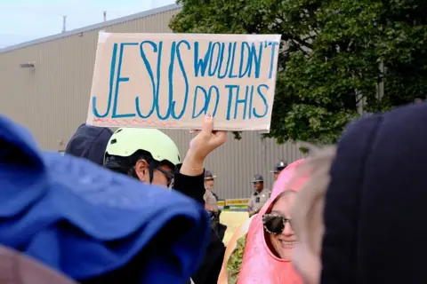 Getty Images A demonstrator holds up a sign saying "Jesus wouldn't do this" during a protest outside the US Immigration and Customs Enforcement detention center in Broadview, Illinois against the latest US immigration crackdown, on October 10, 2025