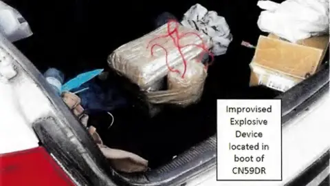 Supplied A grainy image shows a white package with red wires coming out of it in the boot of a car