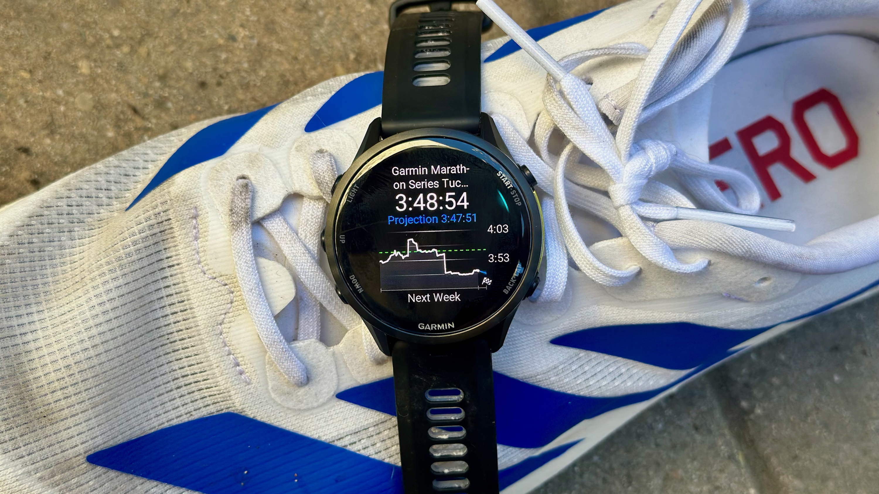 The Garmin Forerunner 970 sitting on a shoe, showing a Race Prediction widget with my projected marathon time for the Garmin Tucson Marathon