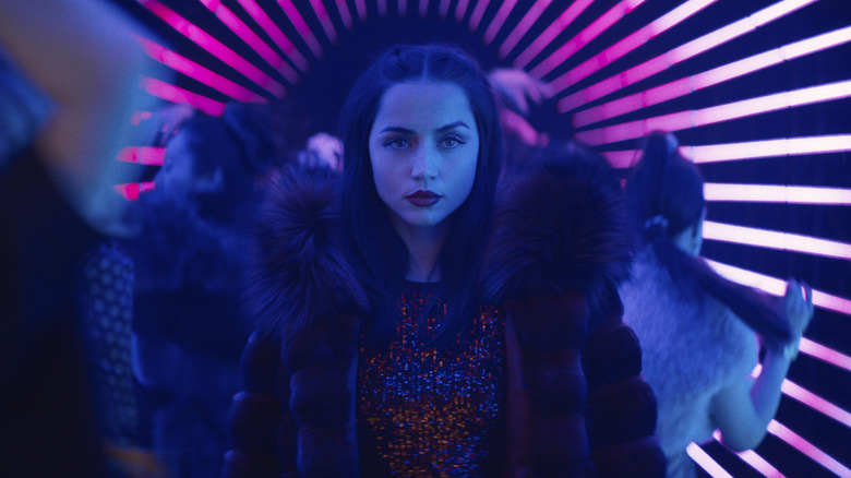 Ana de Armas' Eve Macarro walking among dancing people in Ballerina