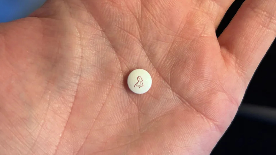 A white tablet with a pregnant woman on it being held in the palm of a hand.