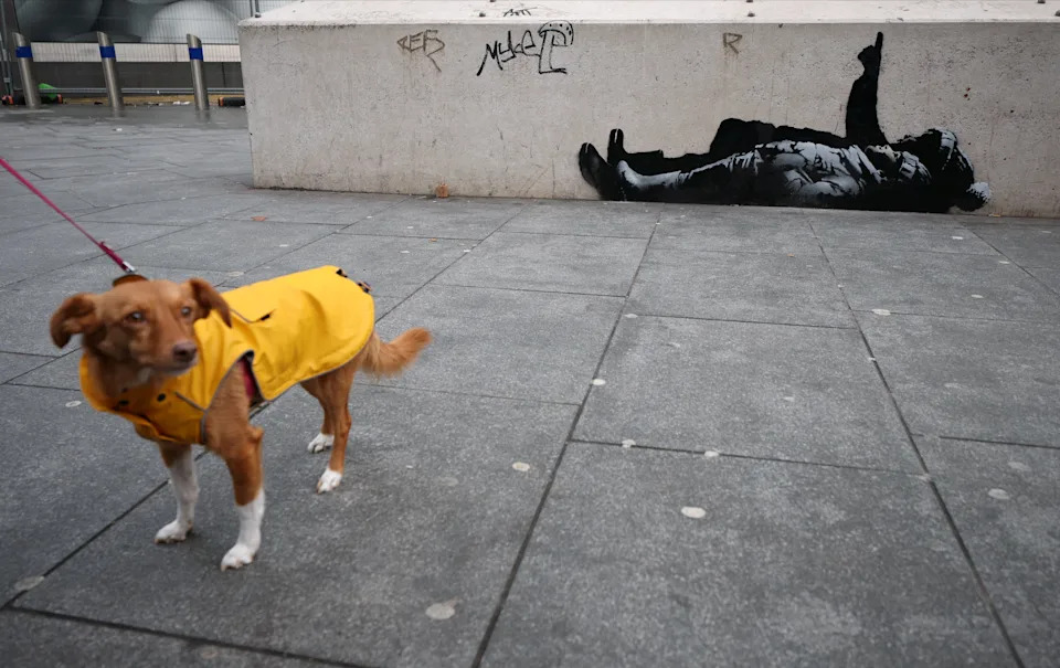 A dog stands beside a new mural reported to be by anonymous artist Banksy, in Tottenham Court Road, London, Britain, December 22, 2025.