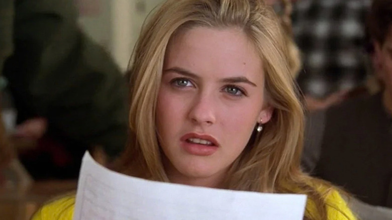 Close-up of Alicia Silverstone as Cher in yellow top holding piece of paper in Clueless