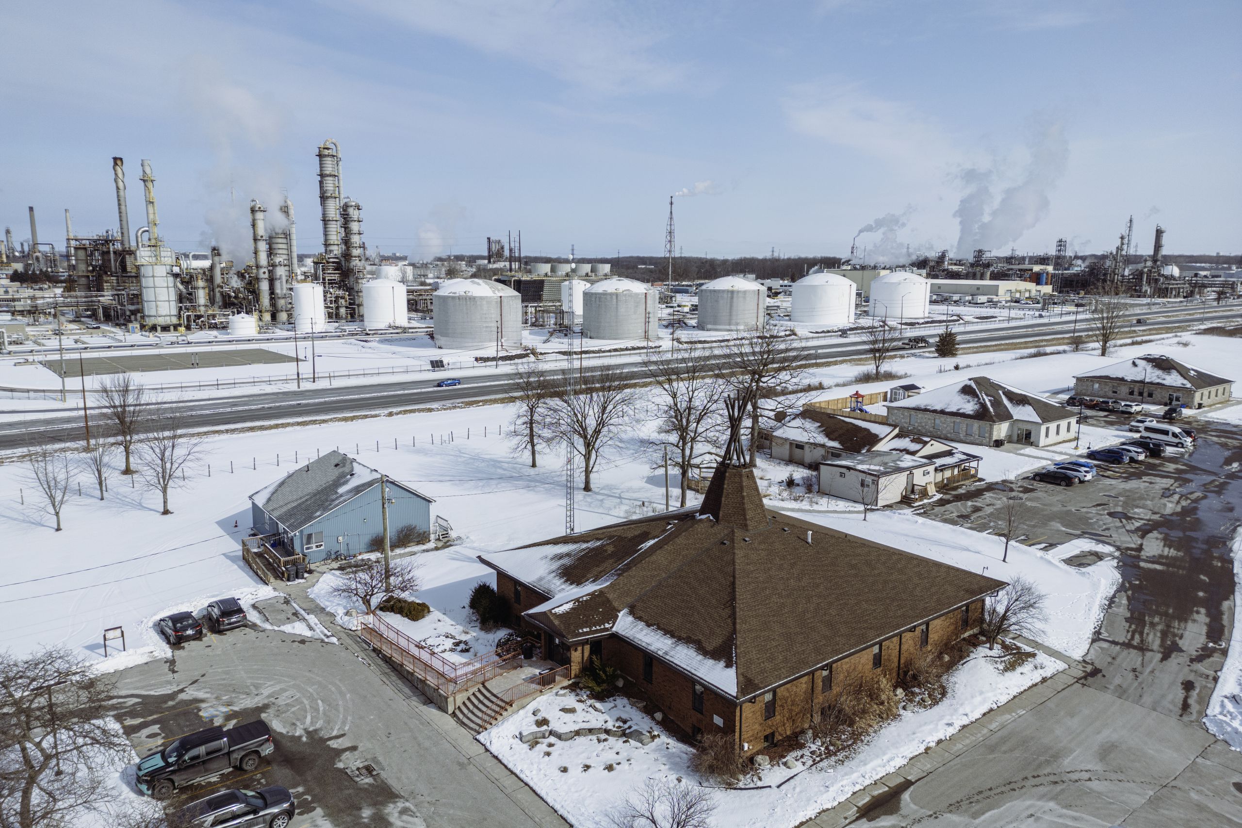 Aamjiwnaang First Nation's band council office in the foreground with smokestacks and fuel storage tanks beyond