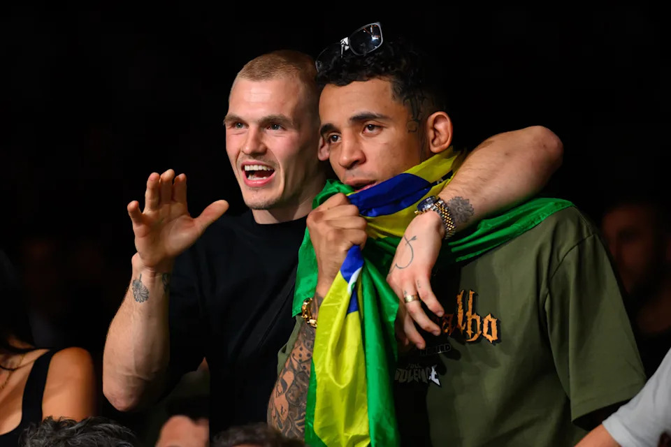 Sep 6, 2025; Paris, FRANCE; UFC Fighters Ian Machado Garry (left) and Carlos Prates (right) watch the fight between Benoit Saint Denis (red gloves) and Mauricio Ruffy (blue gloves) during UFC Fight Night at Accor Arena. Mandatory Credit: Per Haljestam-Imagn Images