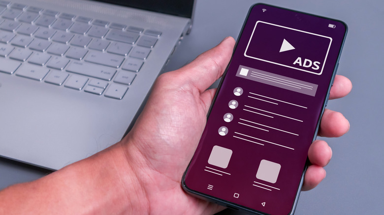 Man holding a phone with a banner ad on display