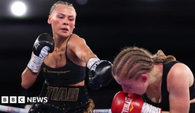Tiah-Mai in the ring, she black boxing gloves on, black short and top, her hair is braided. The other boxer is wearing red gloves and is crouching down in the right hand side.