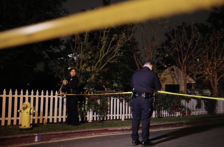 LAPD officers put up police tape as the police investigate two people found dead in Rob Reiner's home on Sunday, in Brentwood, California.