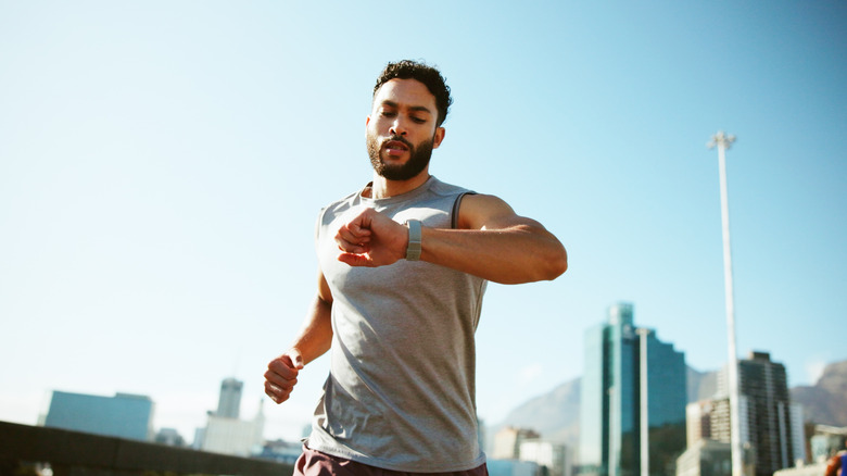 Runner checking wristwatch for steps, calories or monitoring heart rate.