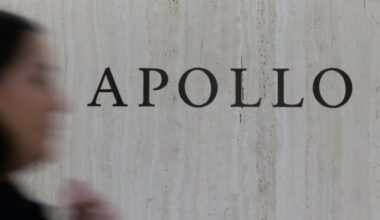 Apollo Global Management signage on a marble wall, with a blurred person passing in the foreground.