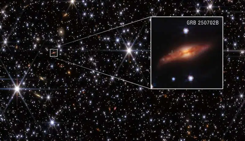 On Oct. 5, NASA's James Webb Space Telescope gave astronomers their clearest view of the host galaxy of a powerful explosion called GRB 250702. The galaxy is so far away its light takes about 8 billion years to reach the Earth. It appears within a star field in the densely packed central plane of our own Milky Way galaxy. In the zoomed inset, tick marks indicate the burst's position near the top edge of the galaxy's dark dust lane. This location eliminates the possibility that the burst was associated with the supermassive black hole at the galaxy's core. Credit: NASA, ESA, CSA, H. Sears (Rutgers). A. Pagan (STScI)