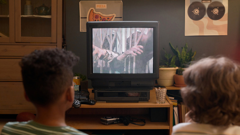 kids watching a movie in a living room, seen from behind