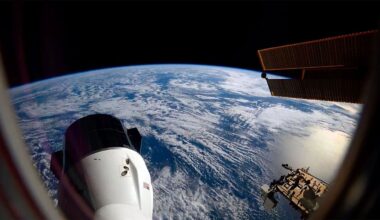the blue waters and white clouds stretch to out to Earth's horizon, set against the blackness of space; in the foreground, a space capsule extends out from a space station