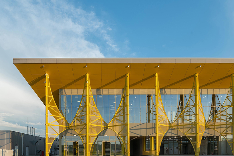 semi-transparent yellow metal arches frame airport’s terminal extension in romania