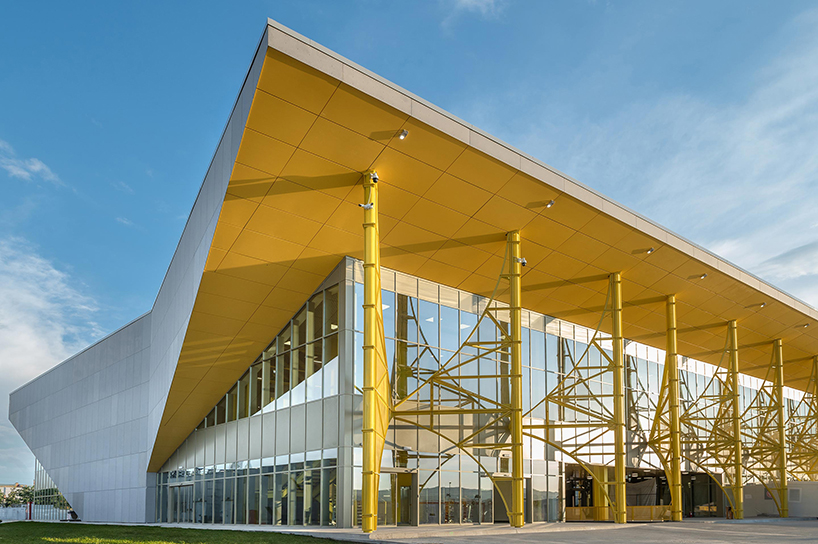 semi-transparent yellow metal arches frame airport’s terminal extension in romania