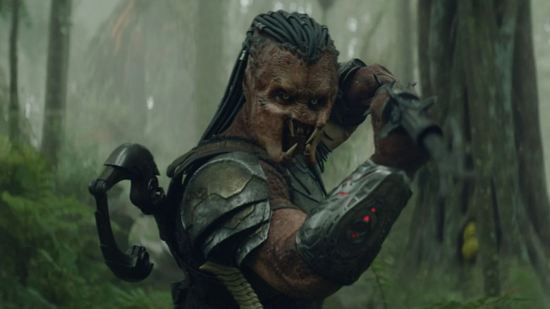 Dek wielding a weapon in the woods in Predator: Badlands