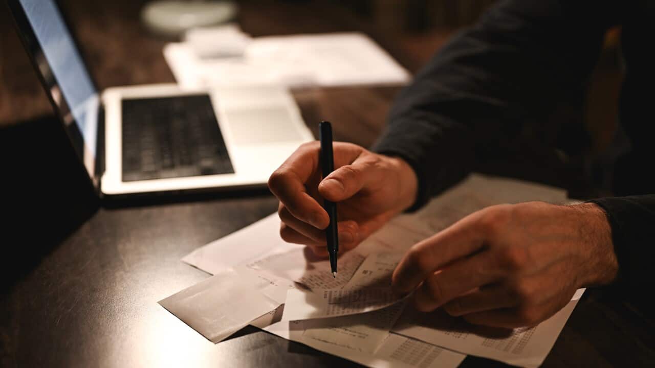 Hands reviewing paperwork and receipts beside a laptop on a desk