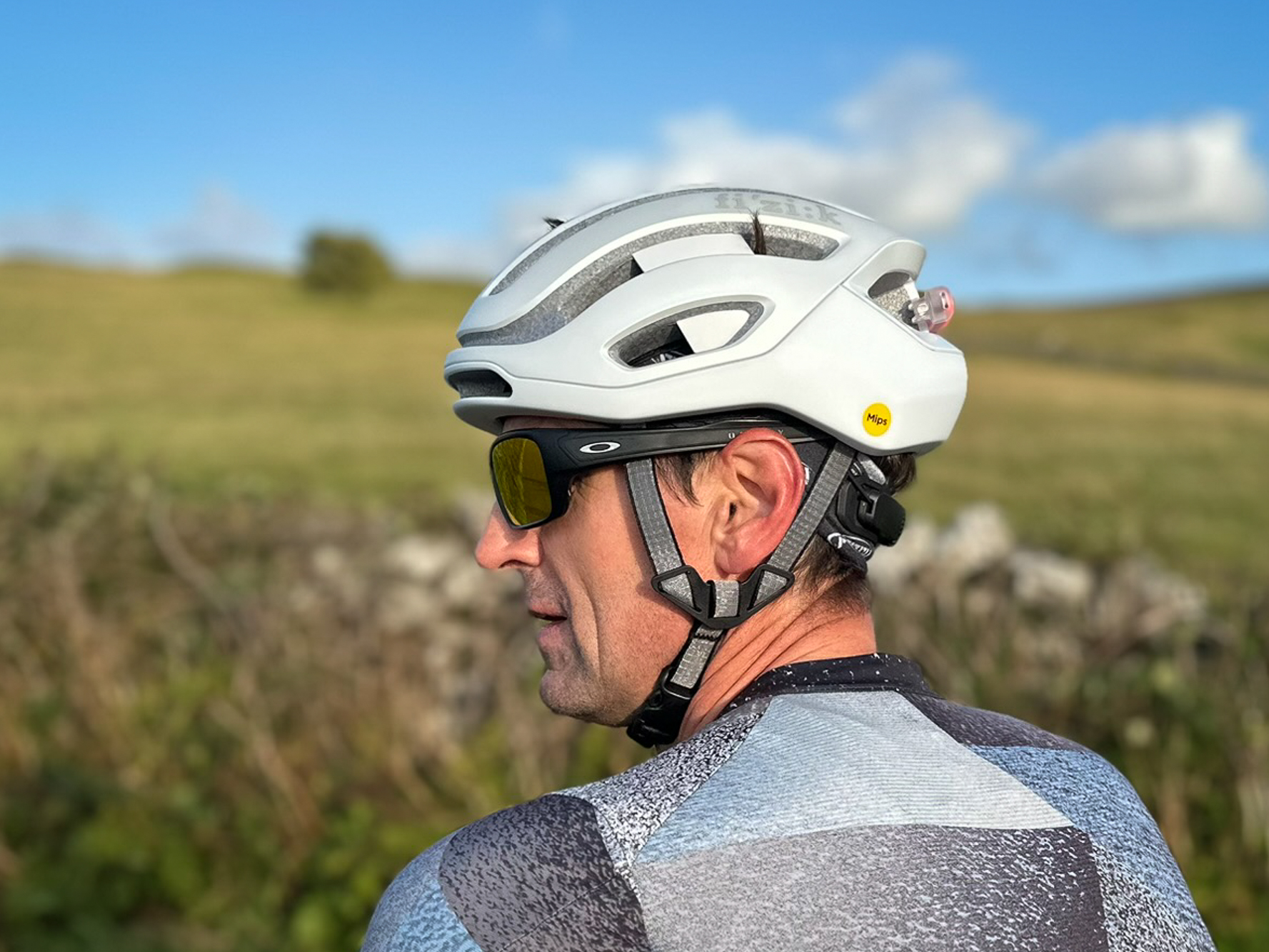 side view of a male cyclist wearing a white Fizik Kudo helmet