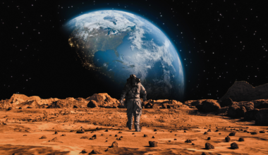 Following Shot of Brave Astronaut in Space Suit Confidently Walking on Mars Towards Earth Planet. Earth Planet as viewed from Mars surface. The surface of Mars, strewn with small rocks and red sand.