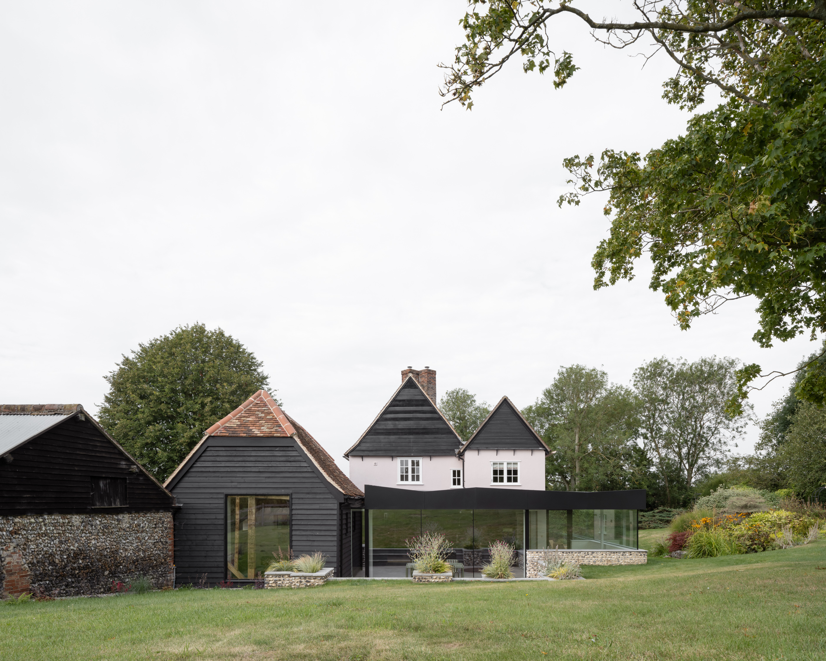 Flint Farm, an old farm building converted into a modern home with extensive glass walls.