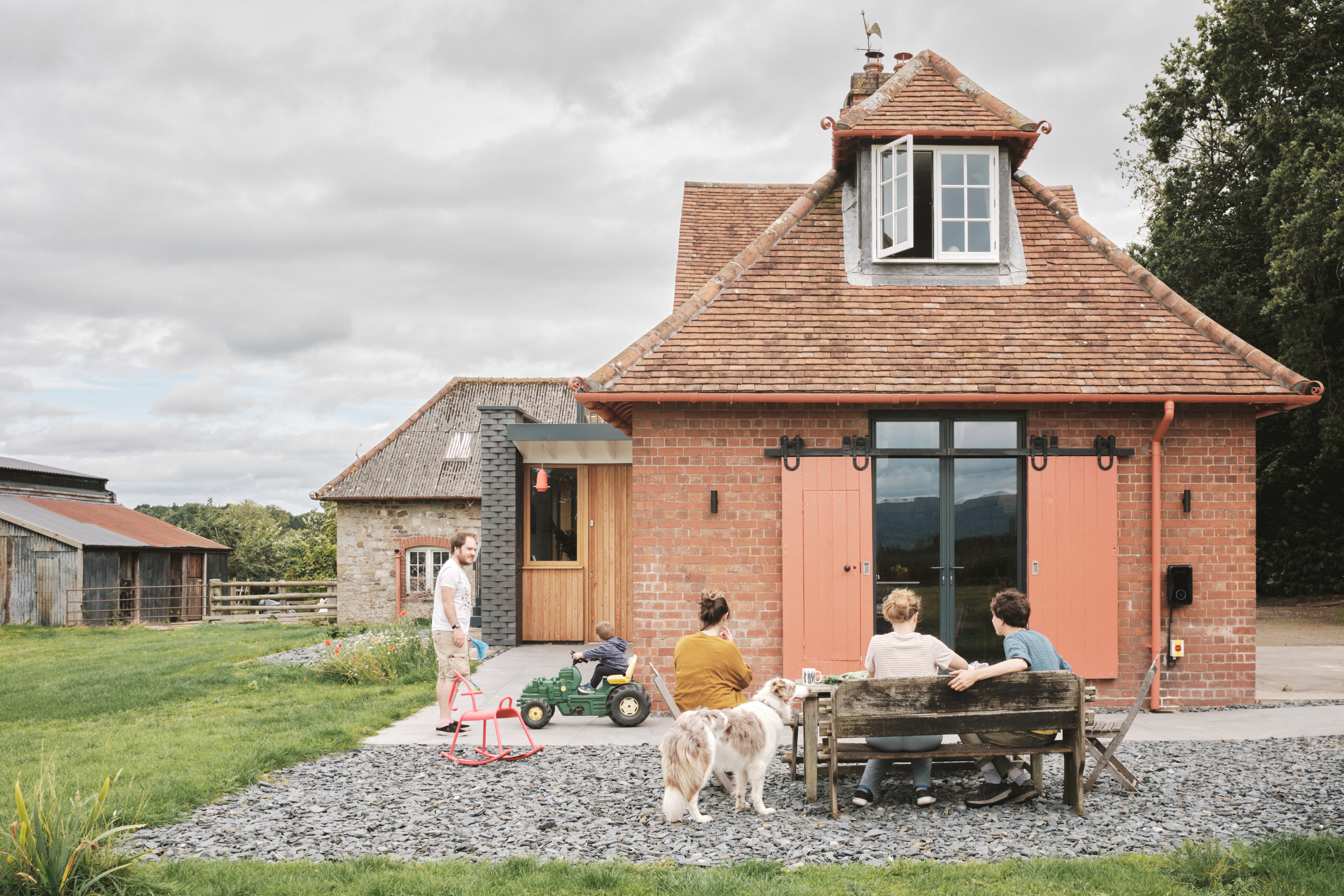 Family enjoying the Plas Hendy Stable Block with a dog on a cloudy day.