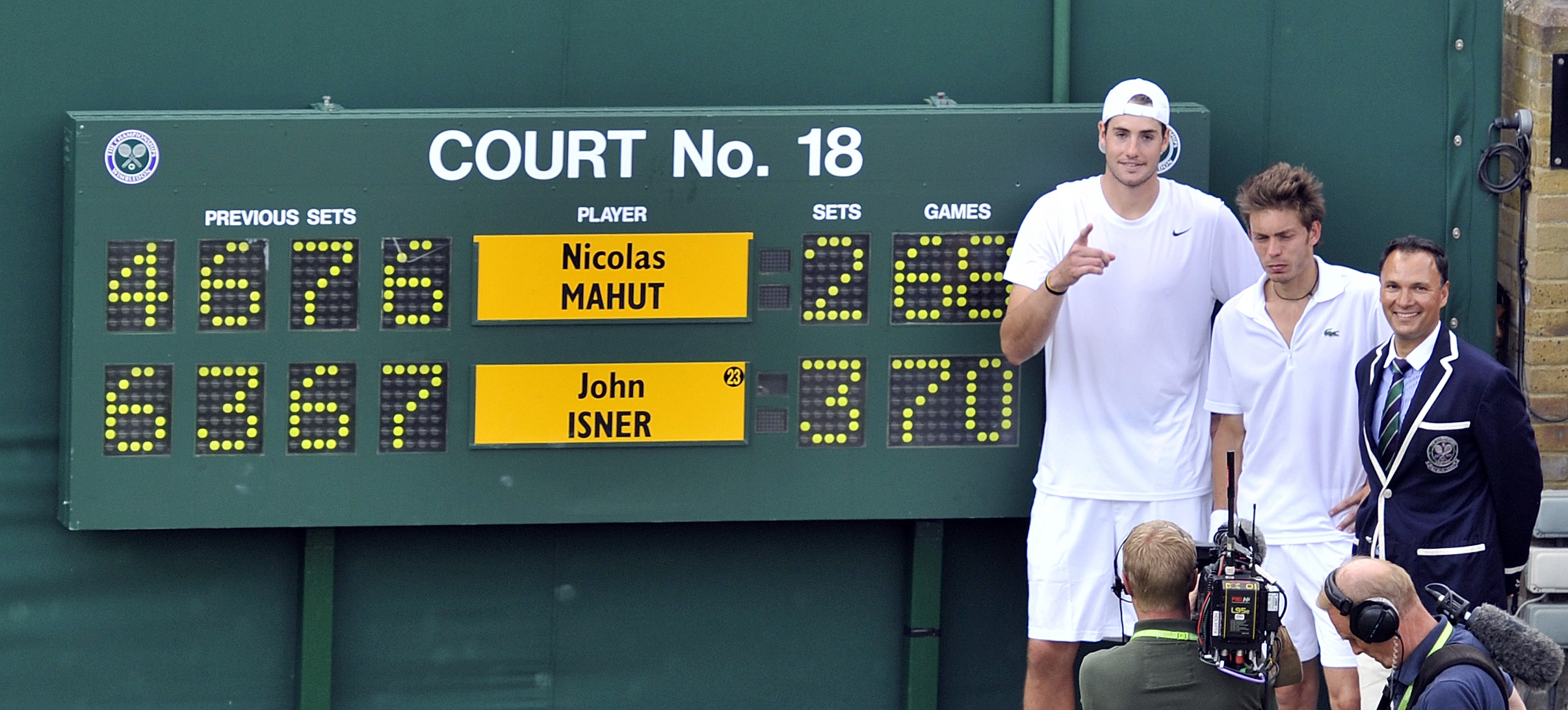 John Isner and Nicolas Mahut stand by the scoreboard after their record-breaking Wimbledon match, with Isner's name highlighted as the winner.